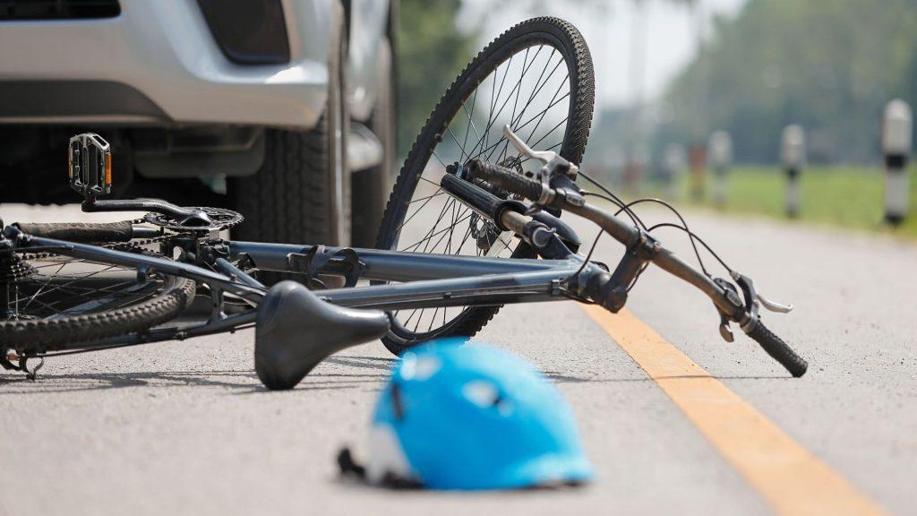 Helmet and damaged bicycle lying on road after accident