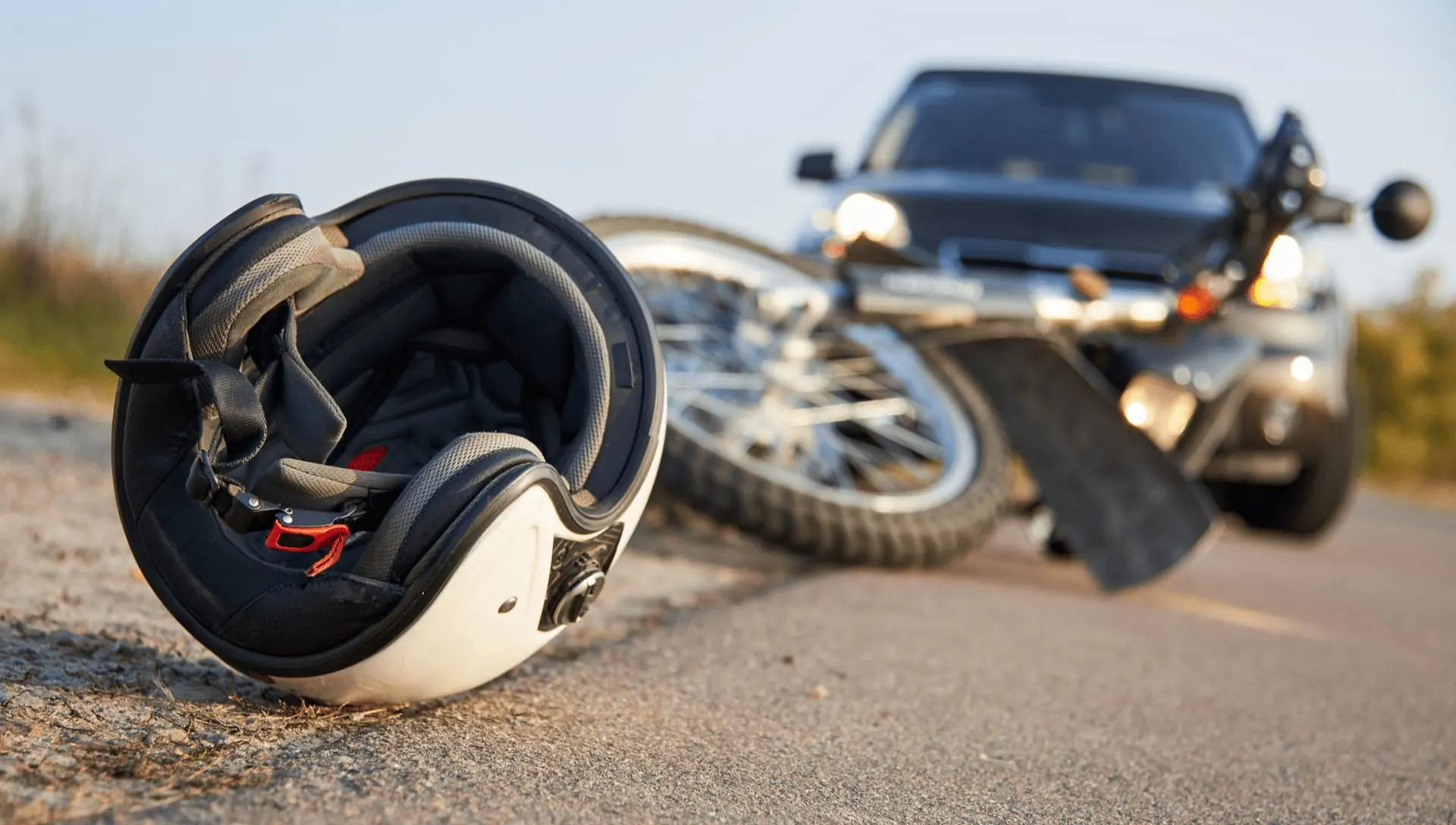A helmet and a downed motorcycle in the road in front of the car that struck it